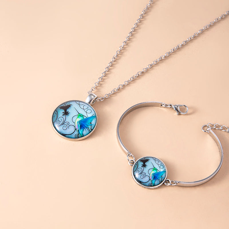 Silver tone hummingbird jewelry set with round blue glass cabochon necklace and bracelet