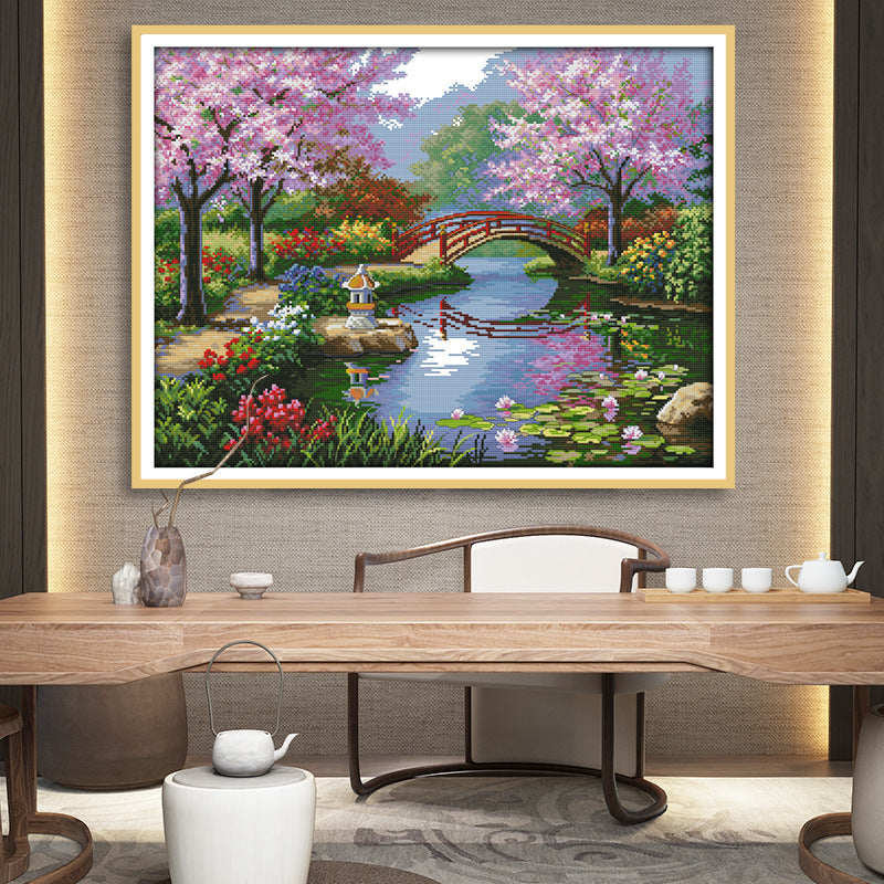 Framed spring river diamond painting on wall with pond, flowers, and red bridge