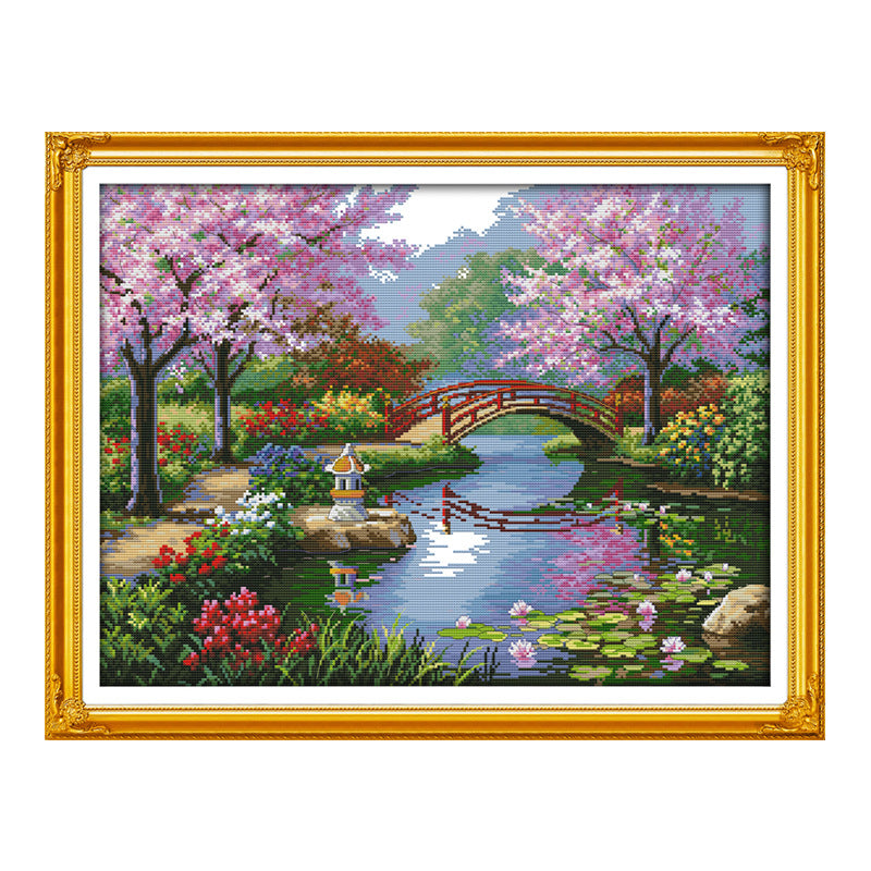 Ornate gold-framed spring river diamond painting with blossoming trees and red bridge