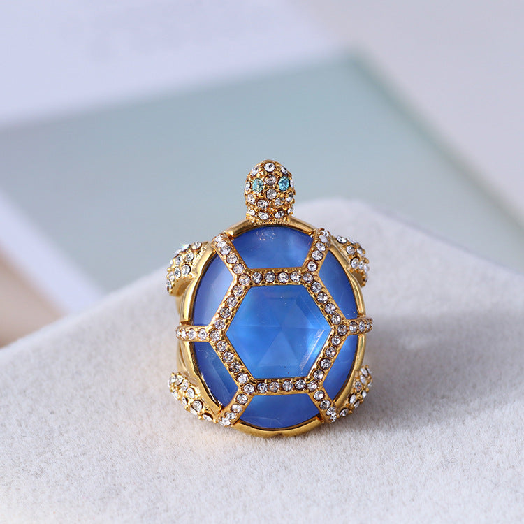 Gold turtle-style ring with faceted blue stones and clear rhinestone surround