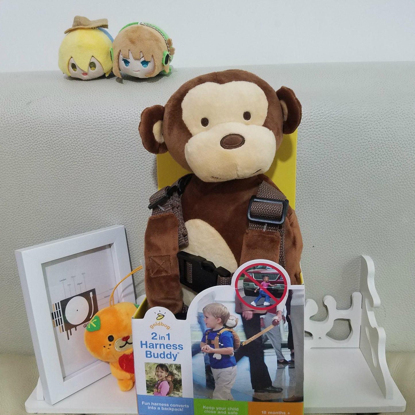 Monkey plush toy with backpack-style safety harness and adjustable straps, front view.