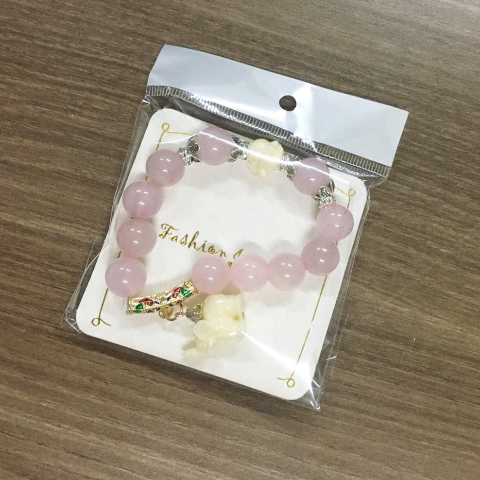Packaged charm bracelet with pink beads and an elephant figurine pendant