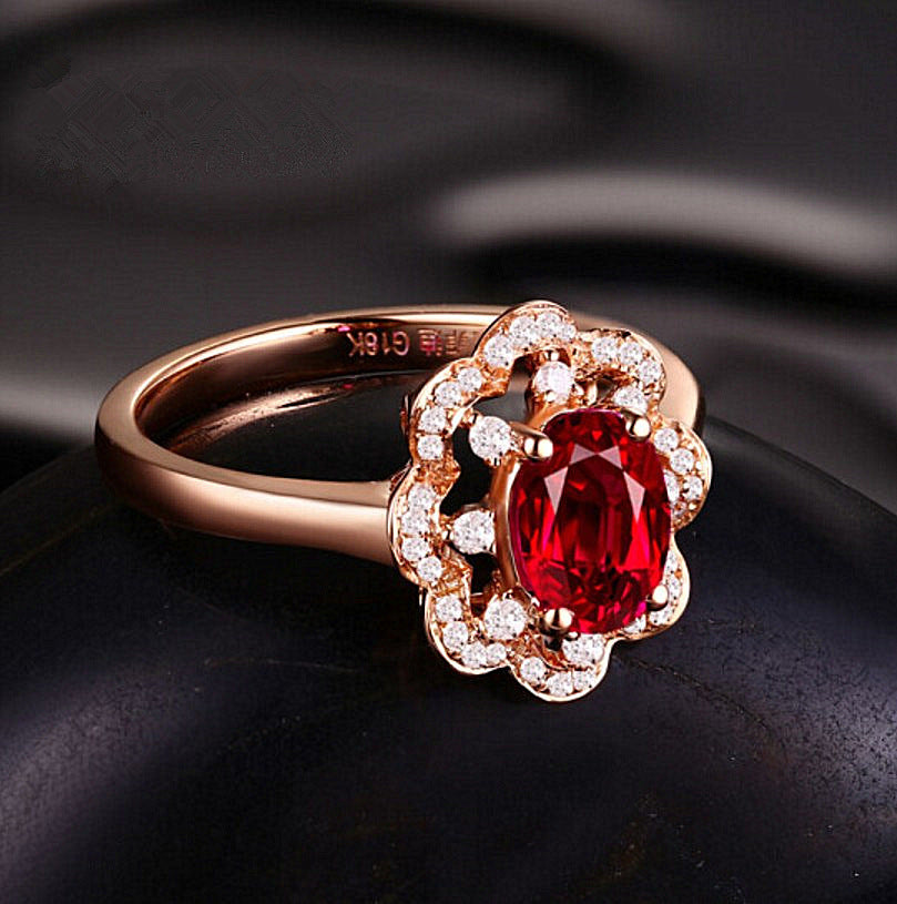 Close-up rose gold ring with oval red ruby and bright white diamond-like halo