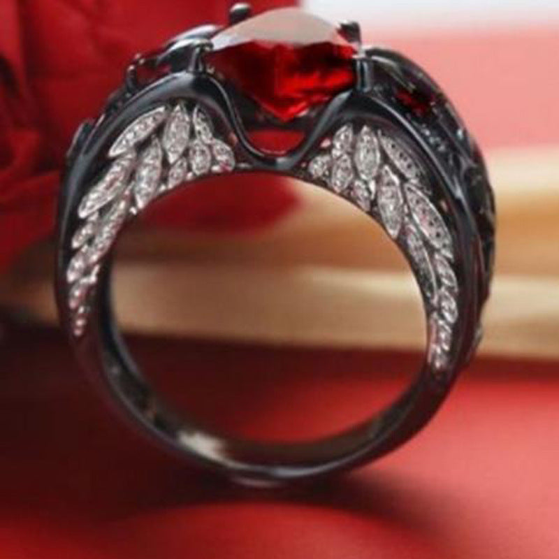 Heart-shaped blue stone ring with dark metal band and sparkling diamond accents