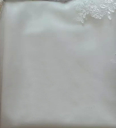 White lace applique fabric detail on a smooth white wedding dress material