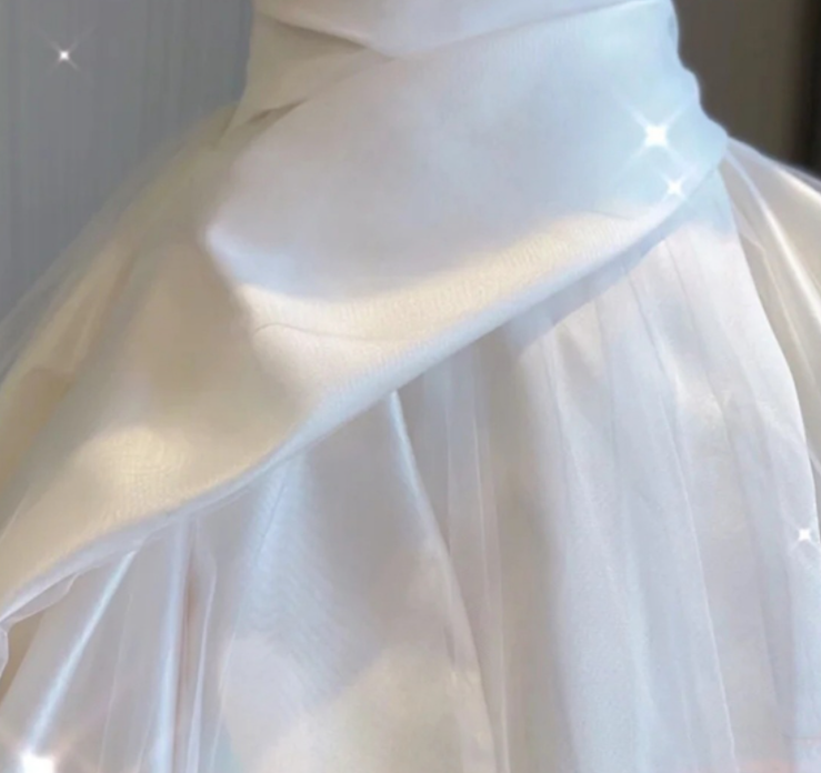 Close-up of white satin off-shoulder bodice with draped fabric and gathered seams