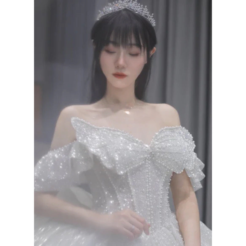 Close-up of one-shoulder beaded bodice on a sparkling wedding dress with tulle sleeve