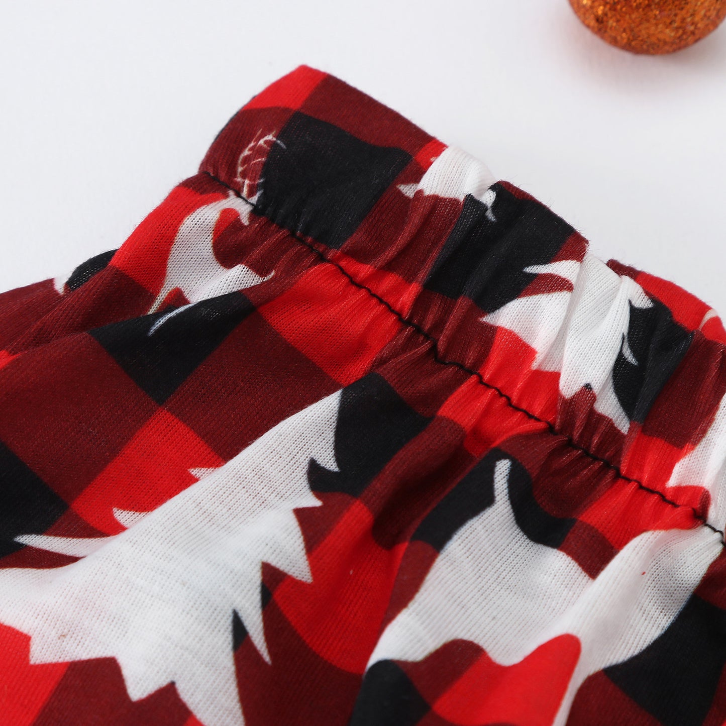 Red and black plaid pajama fabric with white reindeer silhouette pattern