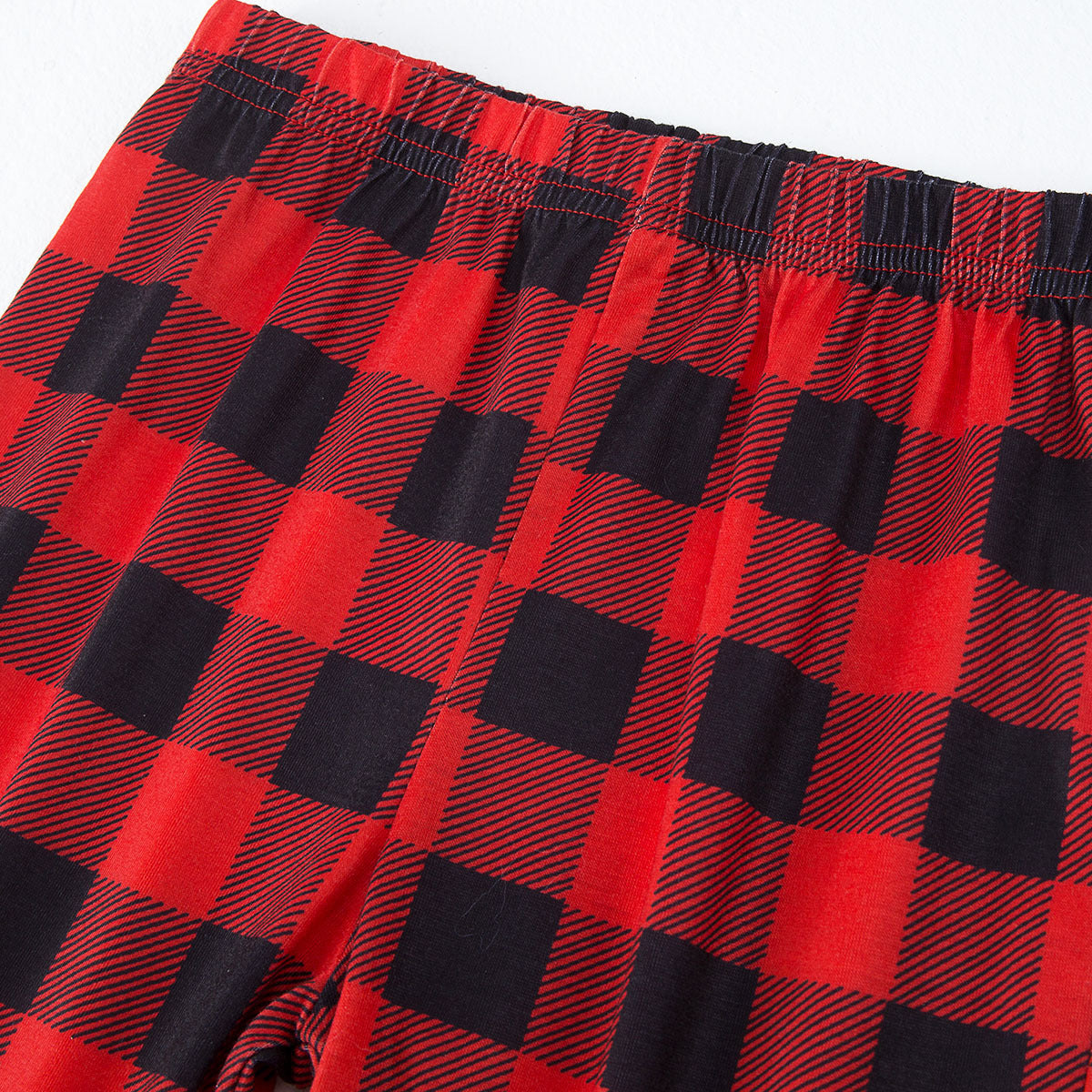 Close-up of red-and-black buffalo plaid pajama fabric with gathered elastic waistband