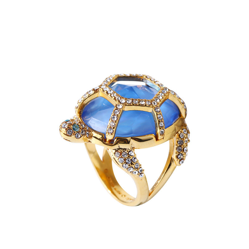 Gold turtle-style ring showing blue stones framed by clear crystals