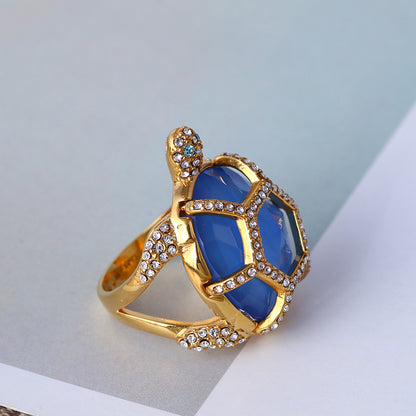 Gold turtle-style ring with blue hexagon stones and clear rhinestone accents