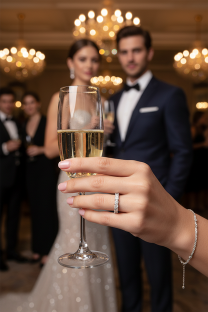 Silver ring with clear stones on finger holding a champagne glass