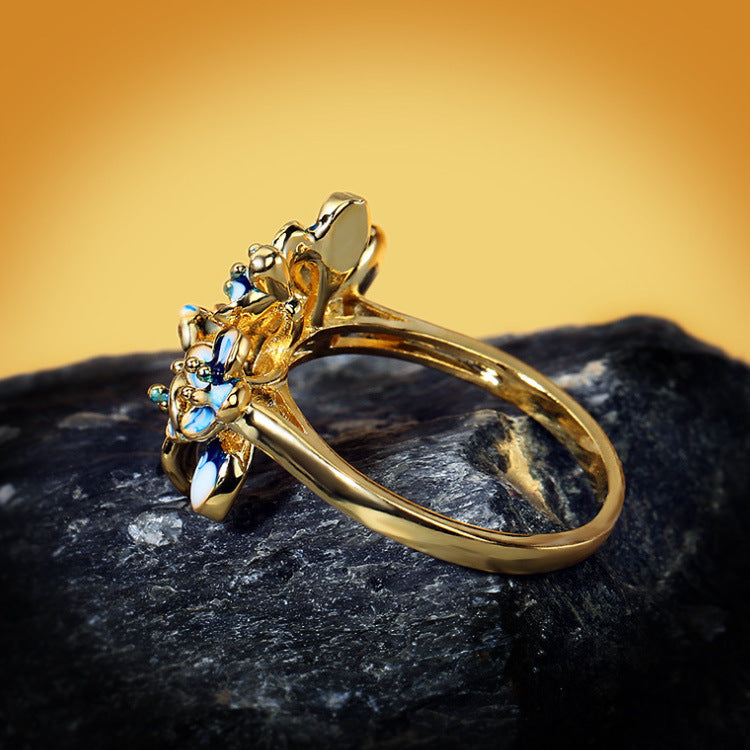 Gold-tone open band ring with blue teardrop gem floral cluster.