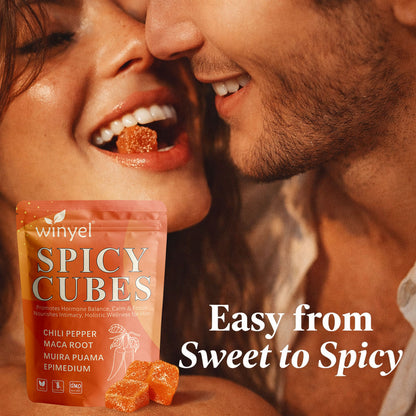 Spicy gummy cubes and pouch with orange cubes in front of a couple’s mouths