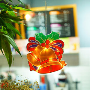 Hanging Christmas bell decoration light with glowing gold bell and red holly bow.