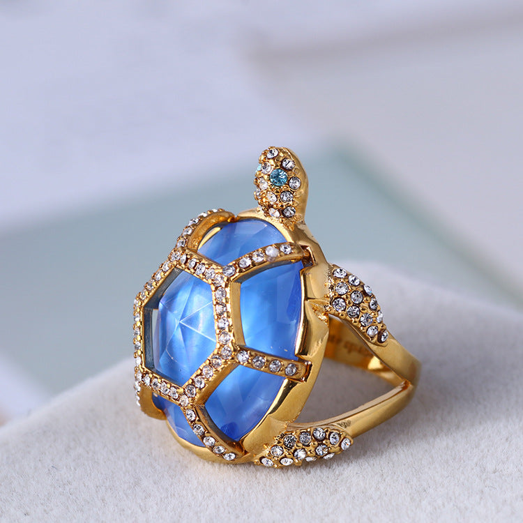 Gold turtle-style ring with three blue facets and clear crystal borders