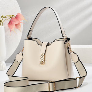 Beige bucket bag with gold clasp, top handles, and adjustable crossbody strap
