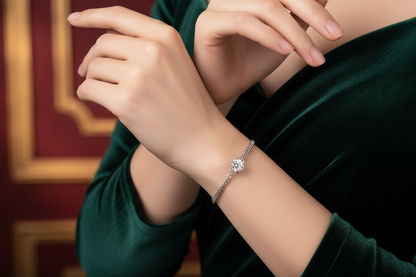 Silver diamond bracelet with round center stone on wrist over dark green sleeve