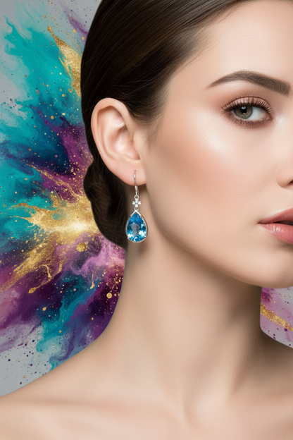 Blue teardrop gemstone drop earrings with ornate silver-toned hooks